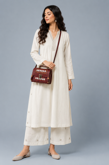 Brown leather cowrie shell trunk bag — lifestyle with white kurta